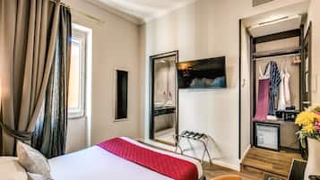A hotel room with a bed, a mirror, a wardrobe, a small table with a vase, and a chair.