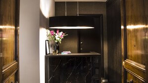 A modern reception area with a marble counter, a vase with flowers, and a hanging light fixture. - Piccola Navona Roof Garden (Rome)