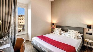 A hotel room with a large bed, a desk with a chair, a window with curtains, and a view of buildings outside. - Piccola Navona Roof Garden (Rome)