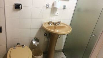 Baño con inodoro, lavabo y cubo de basura.