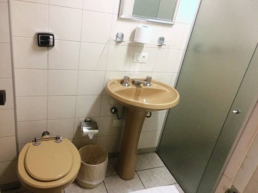 Een badkamer met toilet, wastafel en prullenbak.