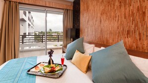 A hotel room with a balcony, a bed with pillows, a tray with food and drink, and a TV on the wall. - Hotel Calypso & Spa (Toamasina)