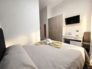 A hotel room with a bed, a desk, a chair, a television, and a wardrobe. - Donn'Anna Bed & Breakfast (Naples)