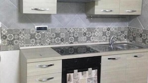 A kitchen with light wood cabinets, a tiled backsplash, a sink, and a stove. - Donn'Anna Bed & Breakfast (Naples)