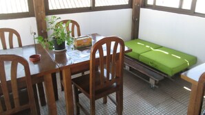 A dining area with wooden chairs and a table, a potted plant, and a green sofa. - Guest House Capitão Mor (Faro)