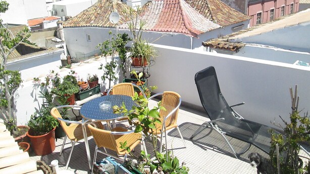 A rooftop terrace with a table and chairs, surrounded by potted plants. - Guest House Capitão Mor (Faro)