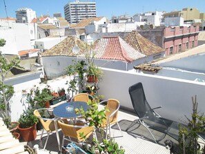A rooftop terrace with a table and chairs, surrounded by potted plants. - Guest House Capitão Mor (Faro)