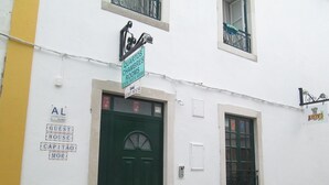 A building with a green door, a sign reading "Guest House," and a window with a metal grill. - Guest House Capitão Mor (Faro)