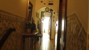 A hallway with a tiled floor, a small table with a plant, and a door with a sign indicating WiFi availability. - Guest House Capitão Mor (Faro)