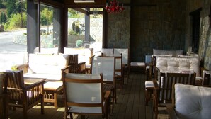 Un área de estar al aire libre con techo, muebles de madera y paredes de piedra.