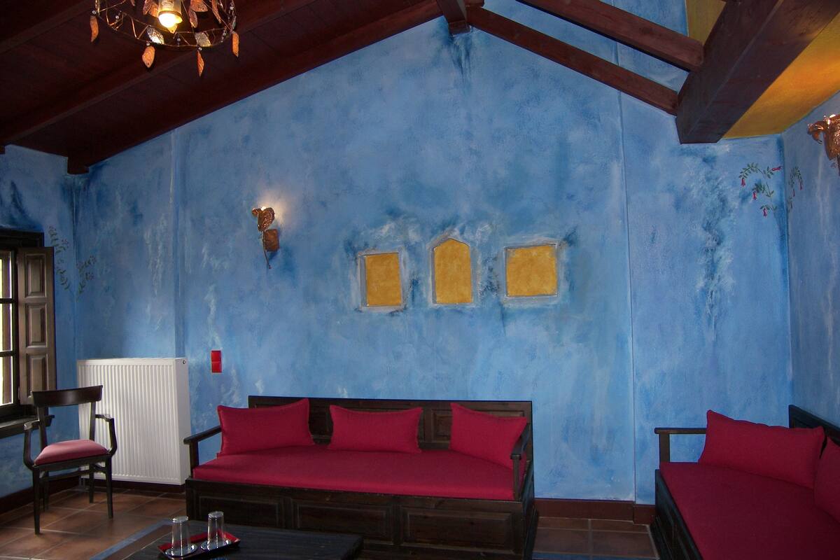 Una habitación con pared azul, techo de madera y sofá rojo.