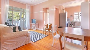 A spacious living area with a sofa, chairs, a dining table, and a kitchen in the background. - Kenwood 7 (Cape Town)