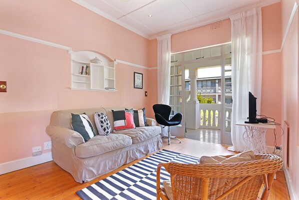 A living room with a sofa, a wicker chair, a television, and a bookshelf.
