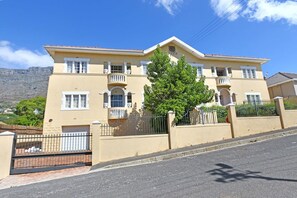 A two-story building with a beige facade, white-framed windows, and a balcony on the second floor.