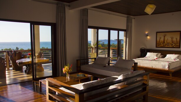 Una habitación amplia con una cama grande, un sofá y un balcón con vistas al océano.