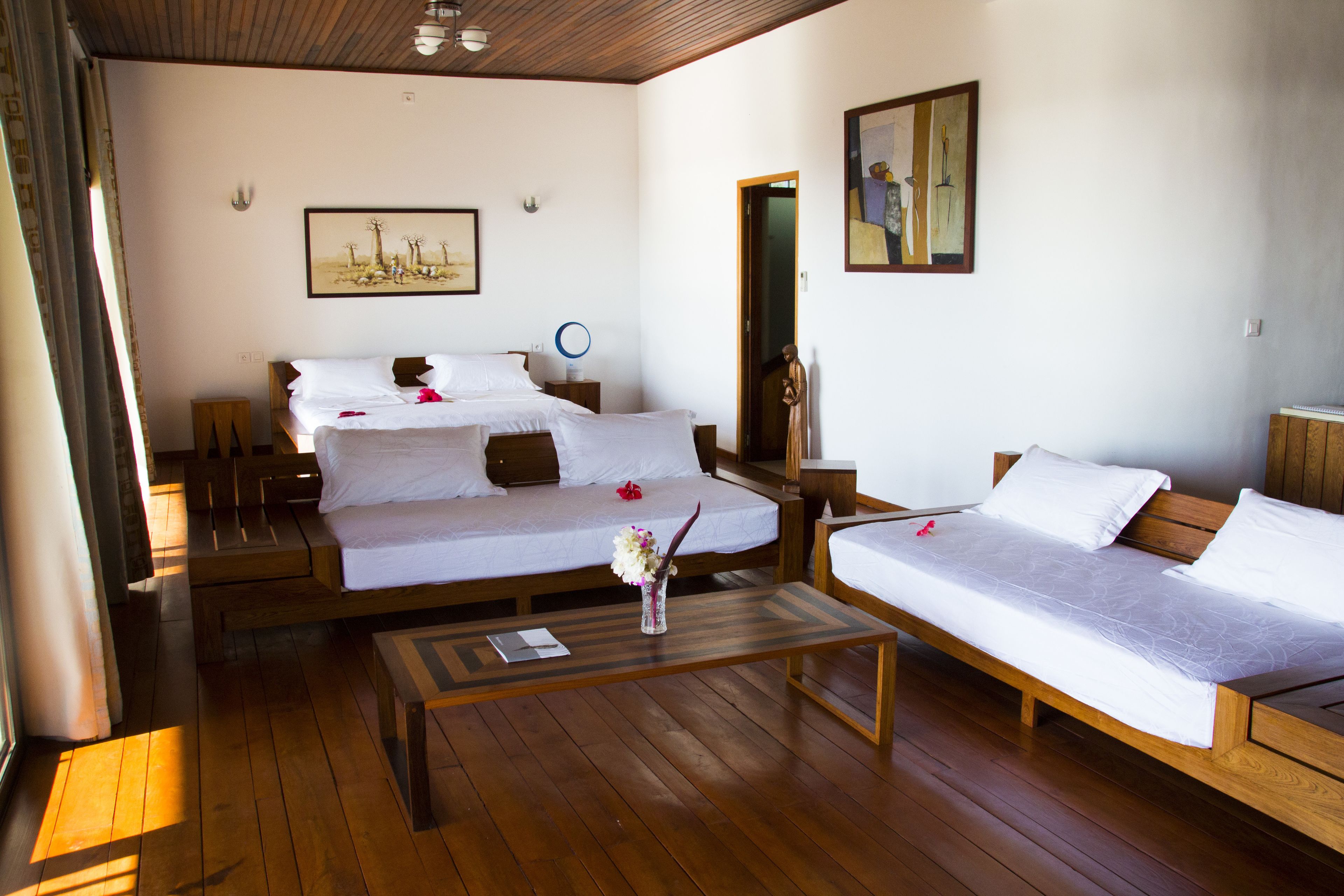 A hotel room with two single beds, a wooden coffee table, and a painting on the wall.