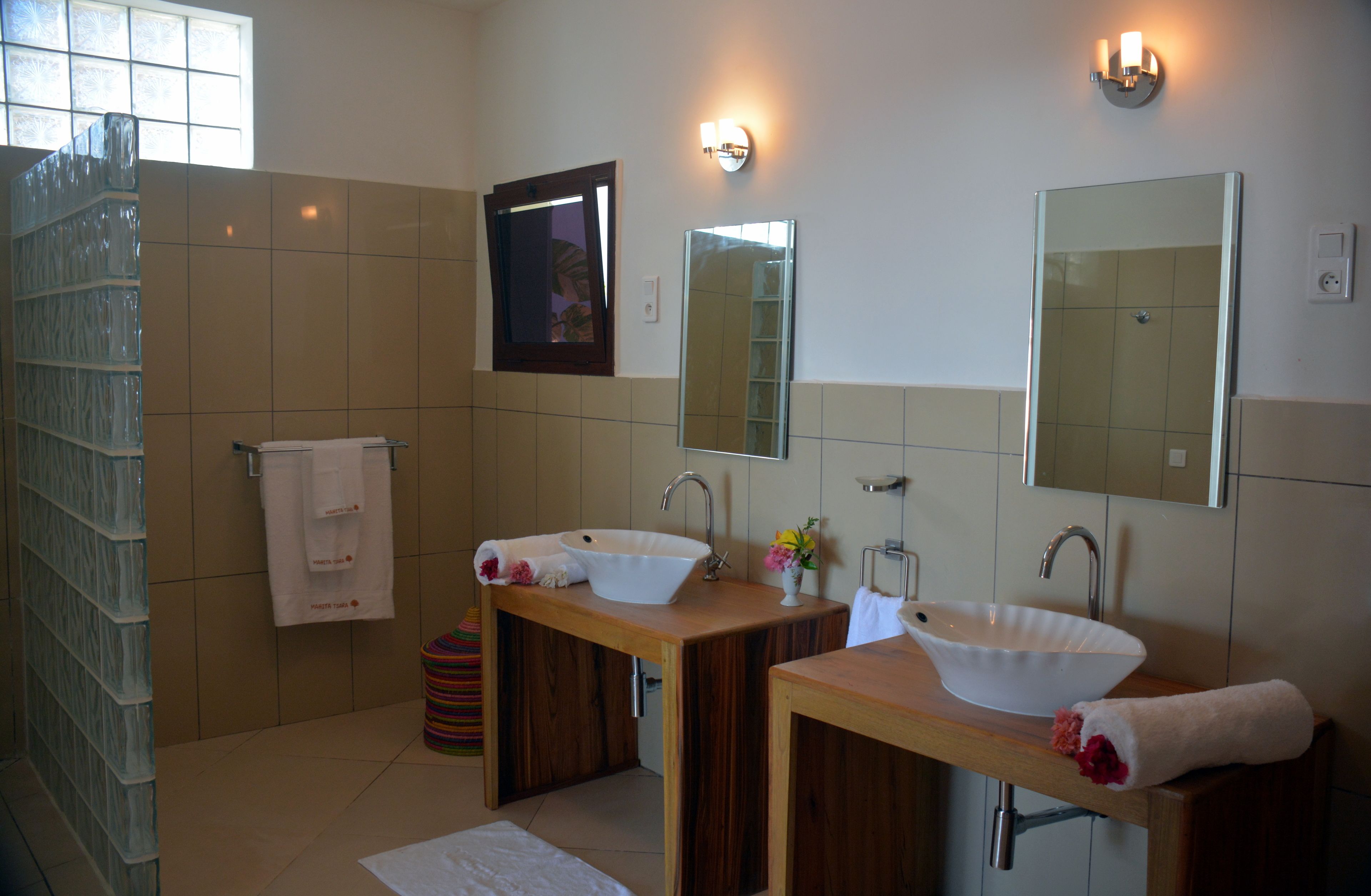A bathroom with two sinks, a mirror, and a shower.