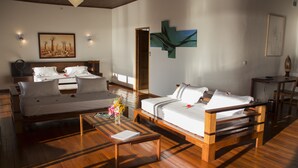 Una habitación de hotel moderna con dos camas, un sofá de madera, una mesita pequeña y obras de arte en las paredes.