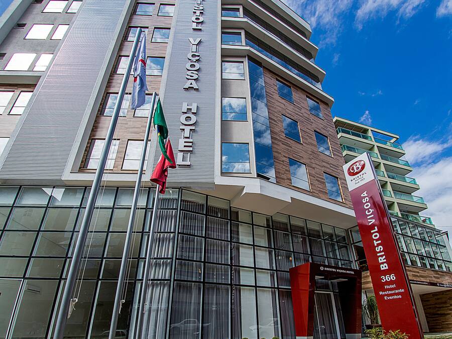 Un hotel moderno con un cartel llamativo, ventanas amplias y un área de entrada bien cuidada.