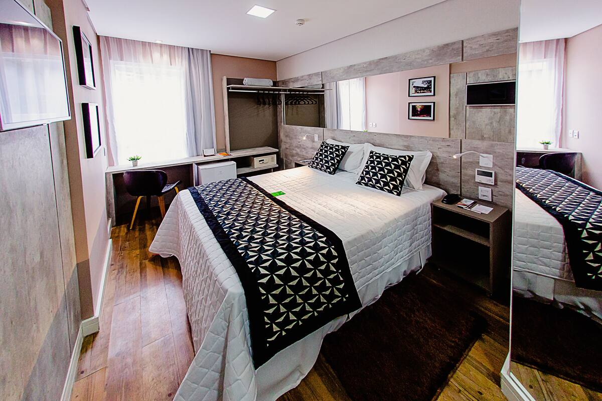 A modern bedroom with a large bed, bedside tables, a wardrobe, and a desk.