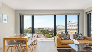 Ein modernes Wohnzimmer mit Essbereich, großen Fenstern und Blick auf die Stadtlandschaft.