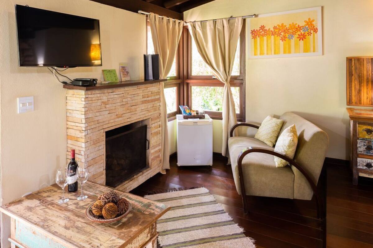 Un salon chaleureux avec une cheminée, un téléviseur fixé au mur, un canapé et une table basse agrémentée d’un tapis.