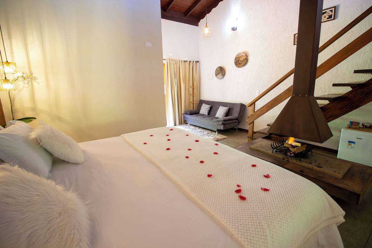 Une chambre à coucher avec un lit, un canapé, une table en bois avec une lampe et un escalier.