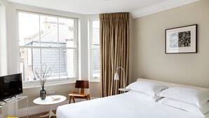 Une chambre d’hôtel avec un grand lit, une télévision, une petite table avec un vase et une chaise.
