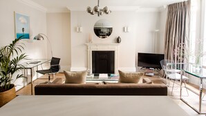 Un salon moderne comprenant un canapé, une cheminée, un téléviseur et un coin repas avec des chaises.
