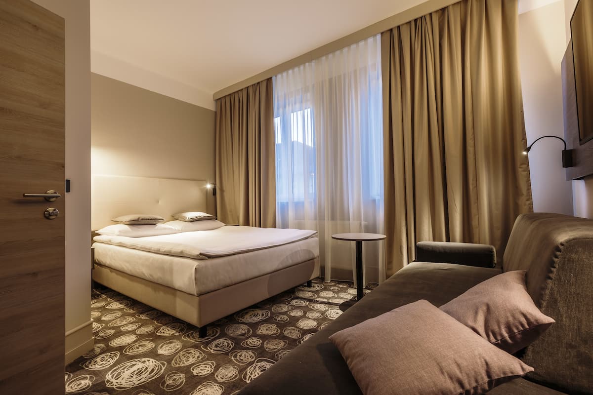 Una habitación de hotel con una cama, un sofá, una mesita y un televisor.