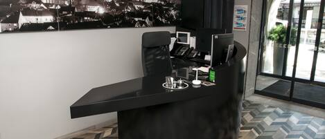 Una recepción con un escritorio, un teléfono y una pequeña mesa con tetera y tazas.