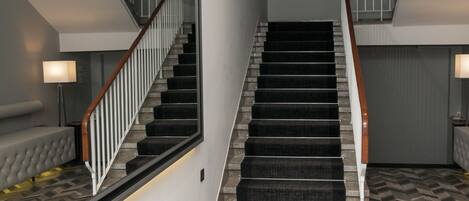 Una escalera de diseño moderno, con barandilla de madera y un rellano alfombrado.