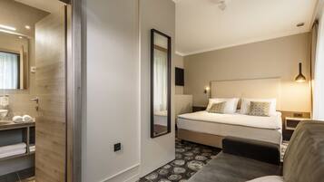 A hotel room with a bed, bedside table, and a mirror.