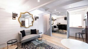 A modern living room with a sofa, coffee table, and a large mirror. - MHL - Maison Hotel Lyon (Lyon)
