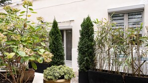 A courtyard with potted plants, a stone pathway, and a building entrance. - MHL - Maison Hotel Lyon (Lyon)