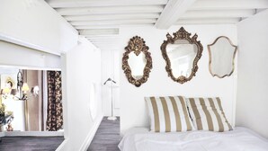 A bedroom with a bed, three wall-mounted mirrors, and a hallway leading to a bathroom. - MHL - Maison Hotel Lyon (Lyon)