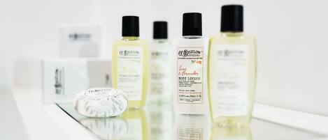 A selection of body lotions and a soap on a reflective surface.