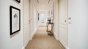 A hallway with white walls, framed artwork, and a carpeted floor. - The Shire Hotel (Rome)
