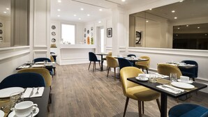 A dining area with tables set for service, chairs in blue and yellow, and a large window with a view. - The Shire Hotel (Rome)