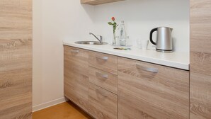 A modern kitchen with light wood cabinetry, a white countertop, and stainless steel appliances. - Hotel City Green Berlin (Berlin)