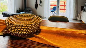 A cozy room with a wooden table, a woven basket, and a view of a red fence through a glass door.