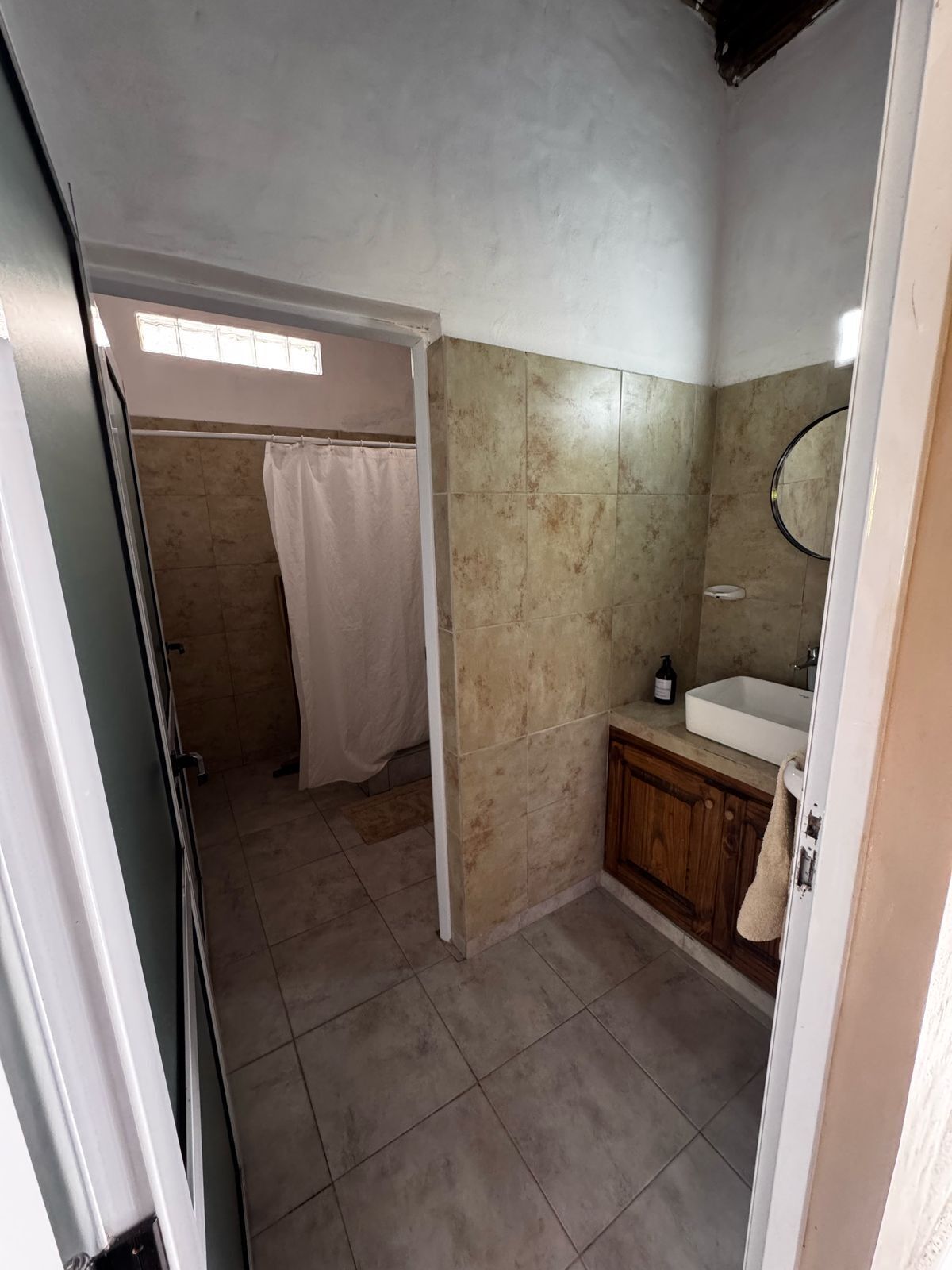 Een badkamer met een douche, wastafel en spiegel.