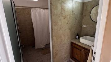 Een badkamer met een douche, wastafel en spiegel.