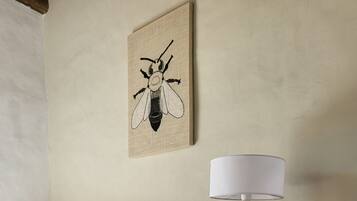 Ein Schlafzimmer mit einem hölzernen Bett, einer Nachttischlampe und einer Insektenillustration an der Wand.
