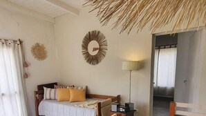 A bedroom with a bed, a wooden table, a lamp, and a woven ceiling light fixture.