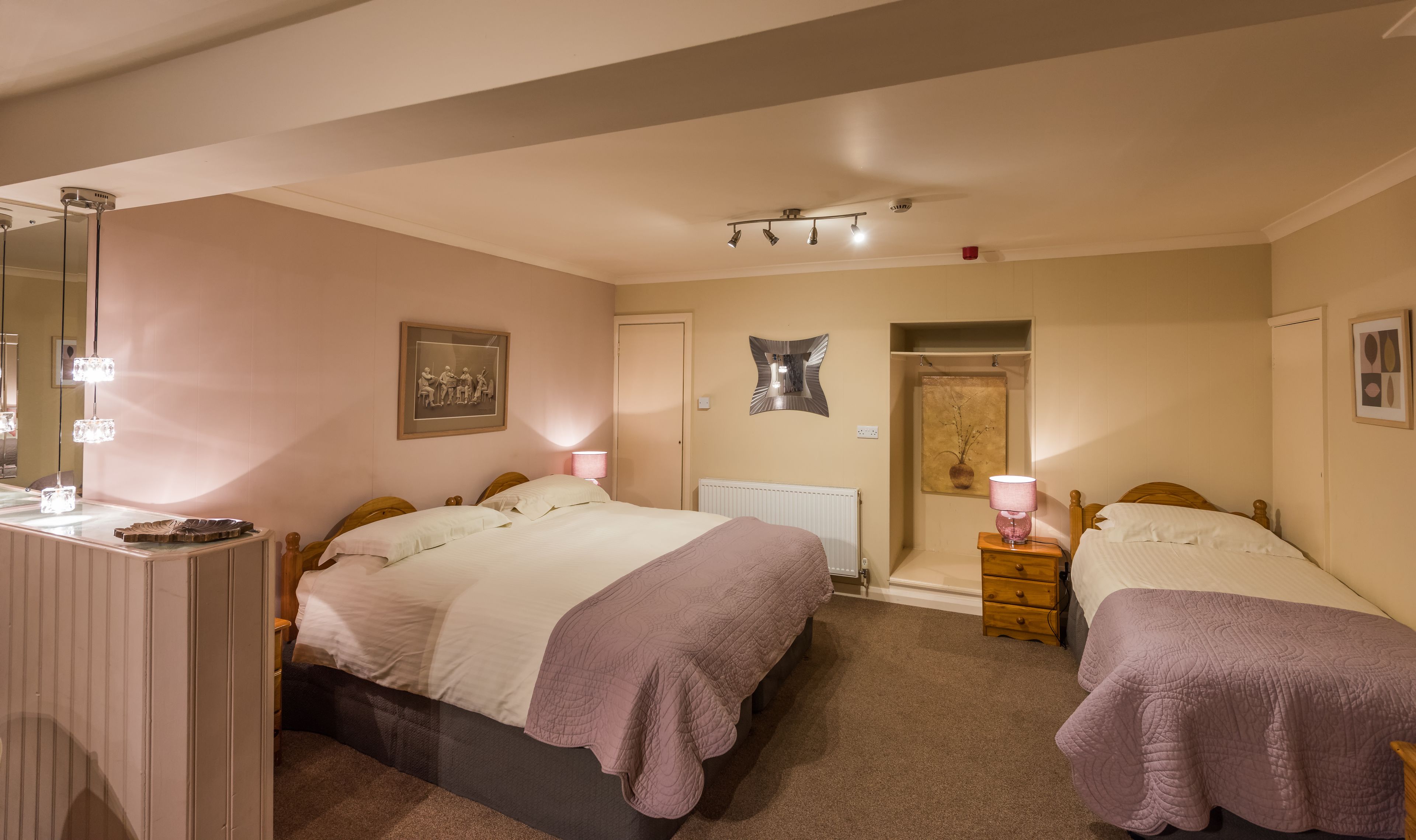 A bedroom with two beds, a dresser, a mirror, and a radiator.