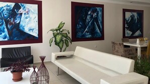 A modern living room with a white sofa, a potted plant, and abstract paintings on the walls. - Sinopark Otel (Sinop)