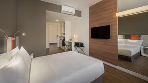 Une chambre d’hôtel moderne équipée d’un grand lit, d’un bureau, d’une chaise, d’un téléviseur à écran plat et d’un miroir.