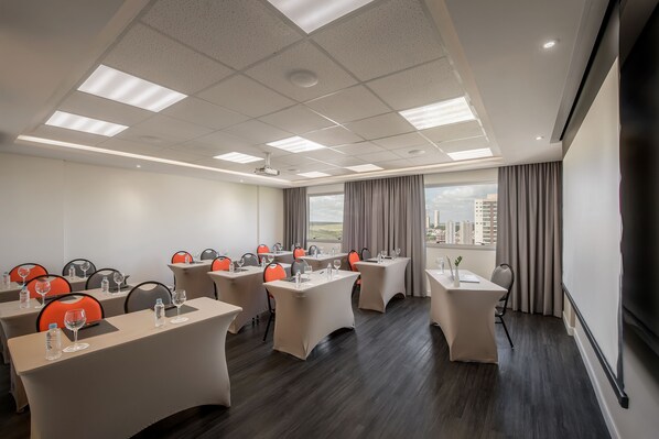 A conference room with tables, chairs, and a large window with a city view. - Intercity Bauru (Bauru)