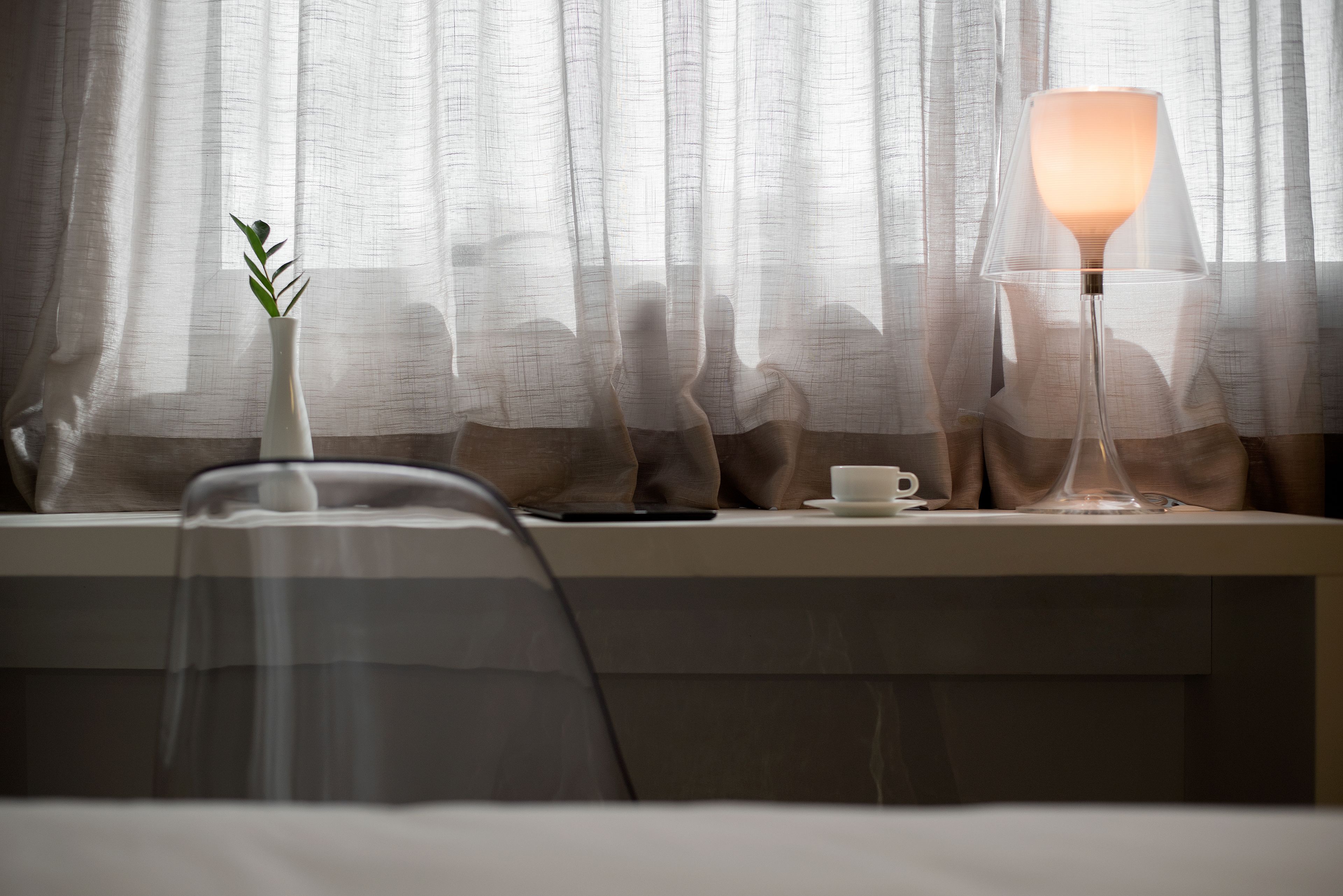 A room with a desk, a lamp, a cup, and a plant.